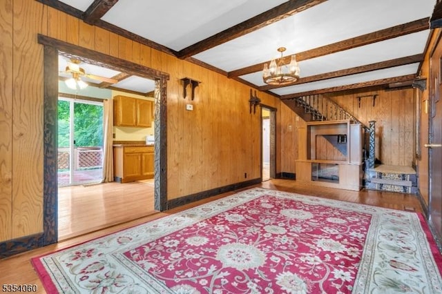 51 Meggins Rd, Rockaway Twp, NJ 07866 - unfurnished living room featuring wood walls, beam ceiling, wood finished floors, a ceiling fan, and a chandelier