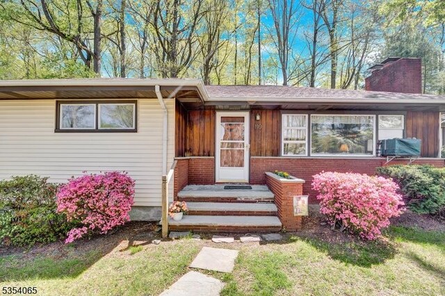 view of front of house featuring a chimney, brick siding, and a front yard