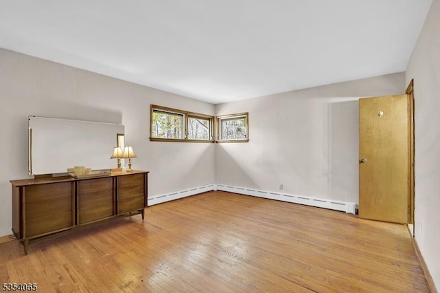 unfurnished room featuring baseboards, hardwood / wood-style flooring, and a baseboard radiator
