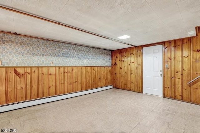 finished below grade area featuring tile patterned floors, a baseboard radiator, and wood walls
