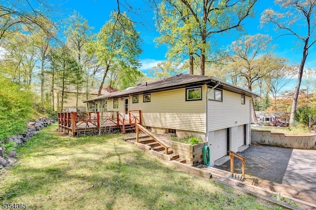 back of house with a lawn, a deck, aphalt driveway, and a garage