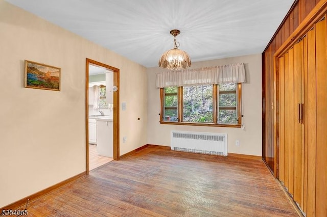 interior space with radiator, baseboards, a chandelier, a sink, and light wood-style flooring