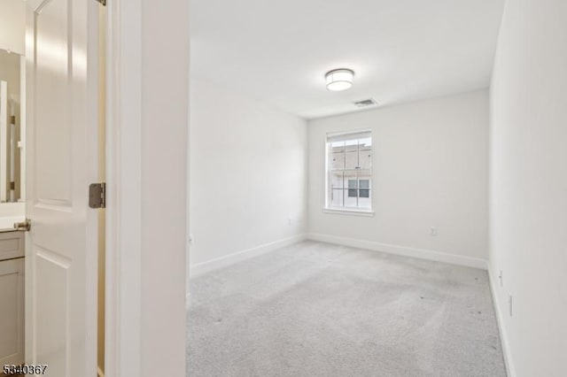 empty room featuring visible vents, baseboards, and light carpet