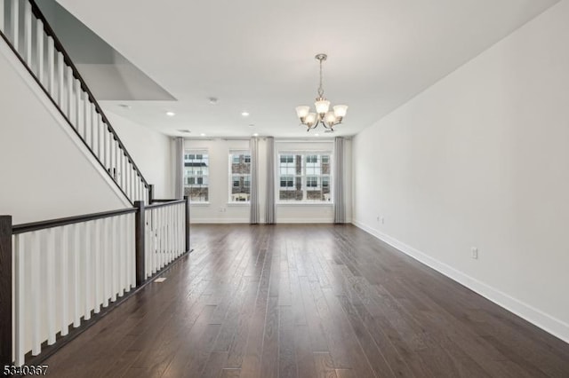 unfurnished living room with baseboards, recessed lighting, dark wood-type flooring, and a chandelier