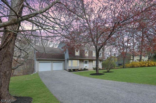 traditional home featuring aphalt driveway, a front yard, and a garage