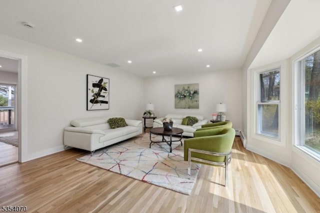 living area with light wood-style floors, baseboards, baseboard heating, and recessed lighting