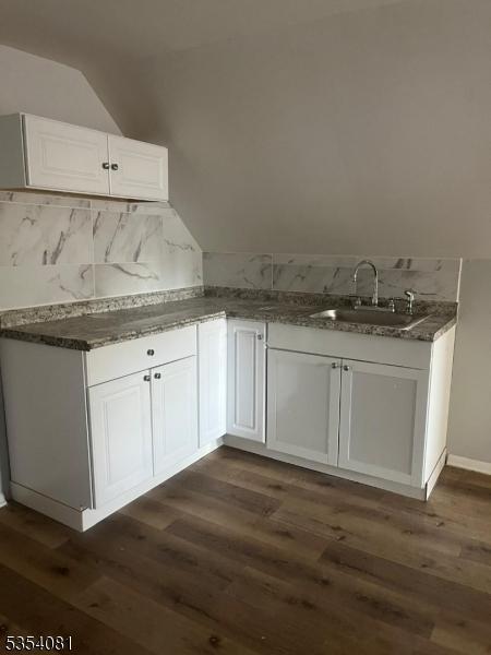 914 S St, Elizabeth City, NJ 07202 - kitchen with dark wood finished floors, a sink, baseboards, lofted ceiling, and white cabinetry