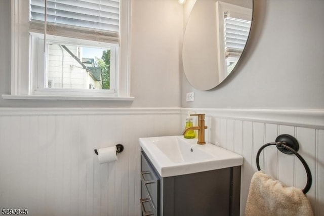 bathroom featuring vanity, a decorative wall, and a wainscoted wall