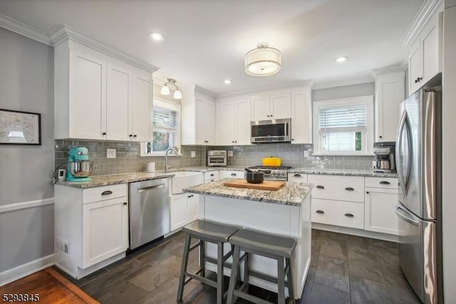 kitchen with crown molding, white cabinetry, a sink, backsplash, and stainless steel appliances