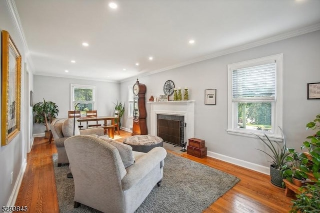 living area with crown molding, wood finished floors, baseboards, recessed lighting, and a tiled fireplace