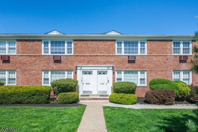 townhome / multi-family property with a front lawn and brick siding