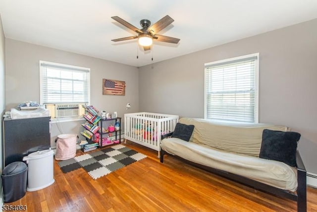 bedroom with ceiling fan, wood finished floors, and cooling unit