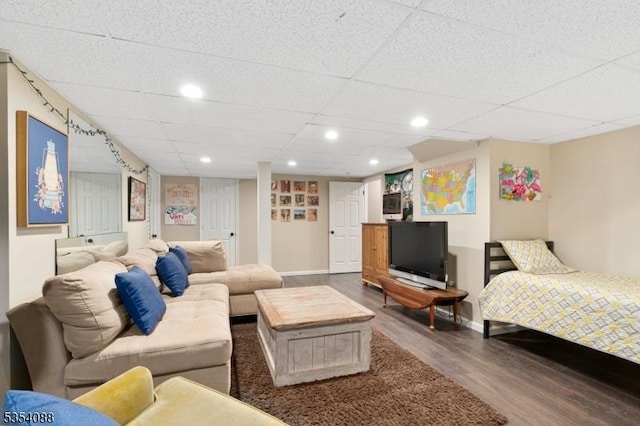 living area with baseboards, recessed lighting, a drop ceiling, and wood finished floors