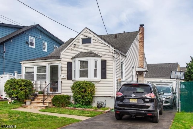 bungalow featuring a shingled roof, fence, and a chimney