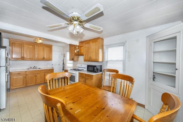 kitchen with brown cabinets, white appliances, light countertops, built in features, and a ceiling fan