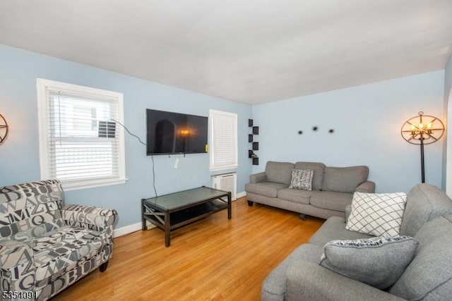 living area with radiator, baseboards, light wood-style flooring, and a chandelier
