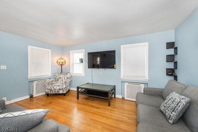 living room featuring light wood-style floors, baseboards, and radiator heating unit