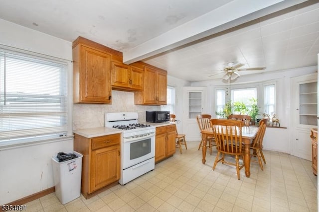 kitchen with a ceiling fan, black microwave, light countertops, beamed ceiling, and white range with gas cooktop
