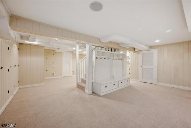 finished basement featuring baseboards, carpet flooring, wood walls, and stairway