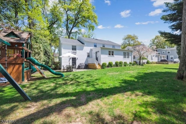 rear view of house with a lawn and a playground