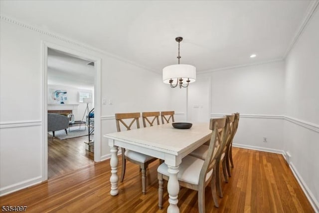 dining space with ornamental molding, wood finished floors, a fireplace, baseboards, and recessed lighting