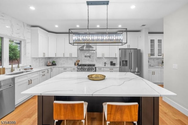 kitchen featuring stainless steel appliances, a sink, recessed lighting, white cabinetry, and a kitchen island
