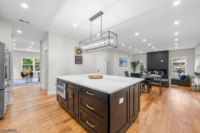 kitchen with light wood finished floors, recessed lighting, a center island, dark brown cabinets, and oven