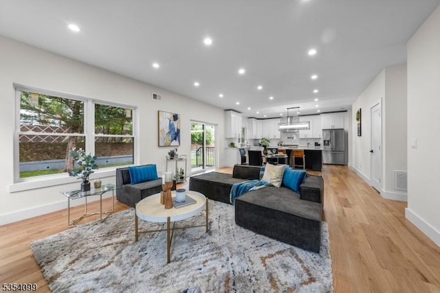 living area with light wood-type flooring, baseboards, and recessed lighting