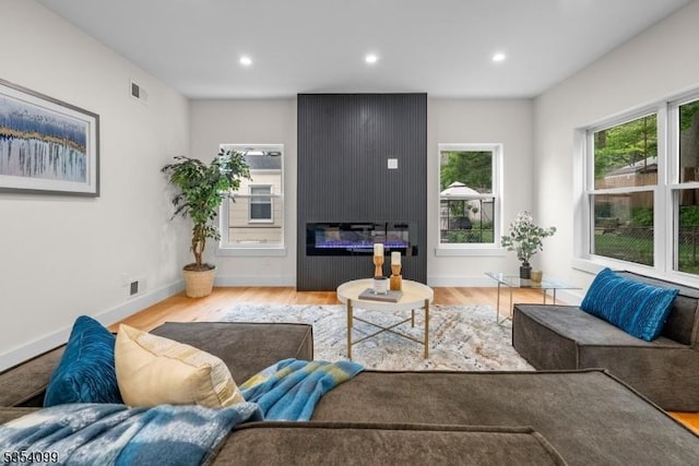 living area with plenty of natural light, wood finished floors, recessed lighting, and baseboards