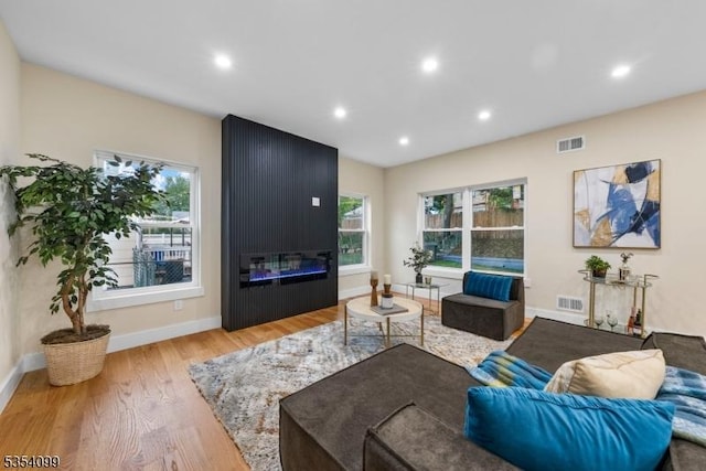 living area with wood finished floors, recessed lighting, a large fireplace, and baseboards