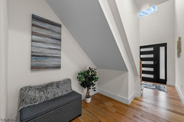 foyer with light wood-type flooring, baseboards, and vaulted ceiling