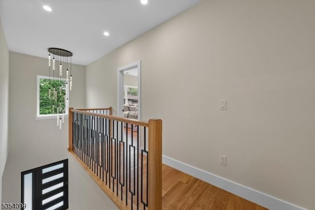 hallway with an upstairs landing, recessed lighting, light wood-type flooring, and baseboards