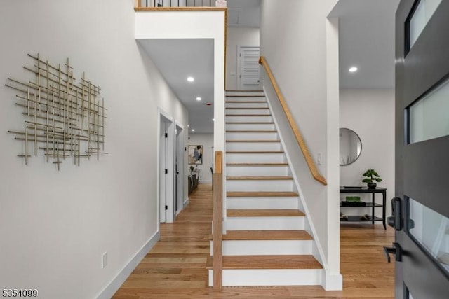 stairs with wood finished floors, baseboards, and recessed lighting
