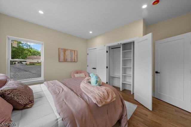 bedroom with wood finished floors, recessed lighting, and two closets