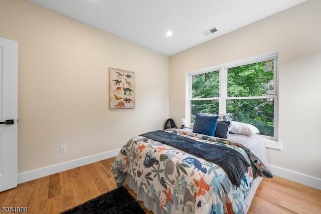 bedroom with baseboards, wood finished floors, and recessed lighting