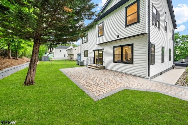 rear view of property with a patio, a lawn, and central AC