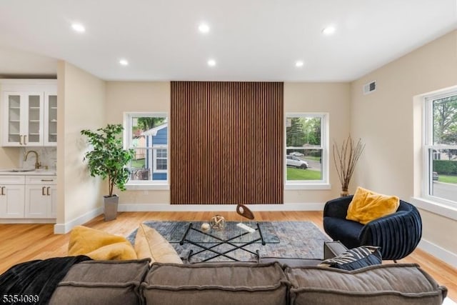living room featuring light wood finished floors, recessed lighting, and baseboards