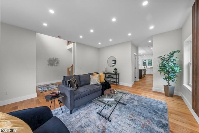 living room featuring light wood-type flooring, recessed lighting, baseboards, and stairway