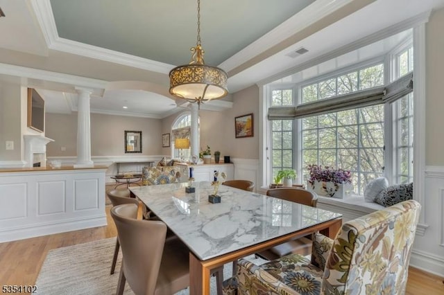 dining space featuring visible vents, decorative columns, a decorative wall, and wainscoting