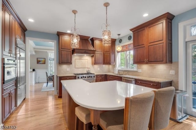 kitchen featuring decorative backsplash, custom exhaust hood, light wood-type flooring, light countertops, and stainless steel appliances