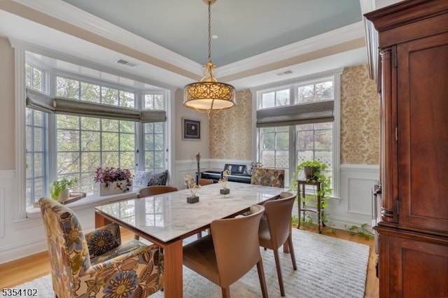 dining room featuring a decorative wall, plenty of natural light, and wainscoting