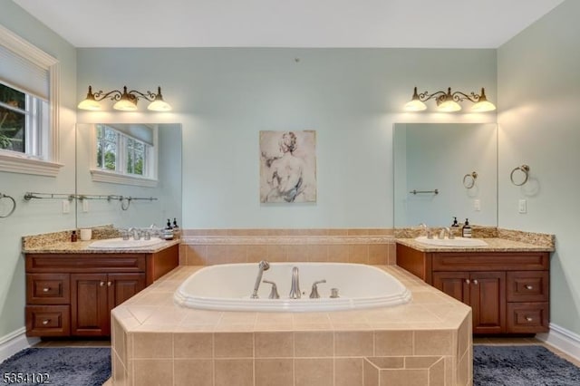 full bath featuring a sink, a garden tub, and two vanities