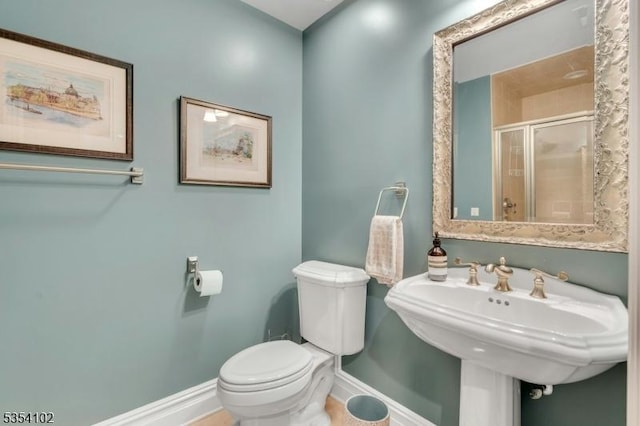 bathroom with baseboards, a sink, toilet, and a shower stall