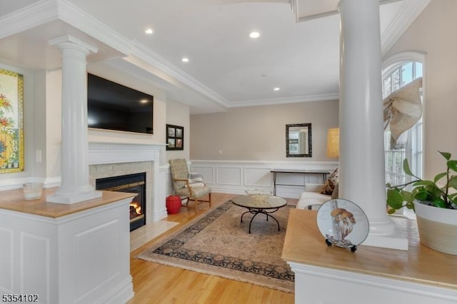 living room featuring ornate columns, a fireplace with flush hearth, wood finished floors, and recessed lighting