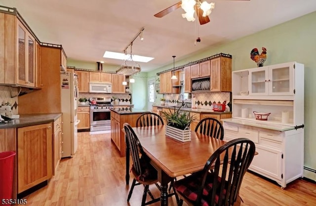 dining area with light wood-style floors, rail lighting, ceiling fan, and a skylight