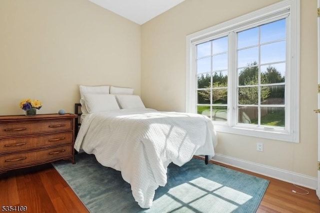 bedroom with baseboards, multiple windows, and dark wood finished floors