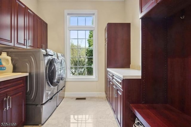 laundry area with visible vents, washer and dryer, baseboards, cabinet space, and light tile patterned floors