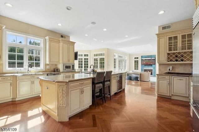 kitchen with visible vents, stainless steel microwave, cream cabinets, and wine cooler