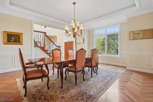 dining space featuring an inviting chandelier, a raised ceiling, ornamental molding, and stairs