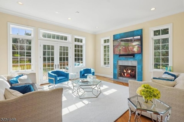 living room featuring a healthy amount of sunlight, ornamental molding, french doors, and a fireplace with flush hearth
